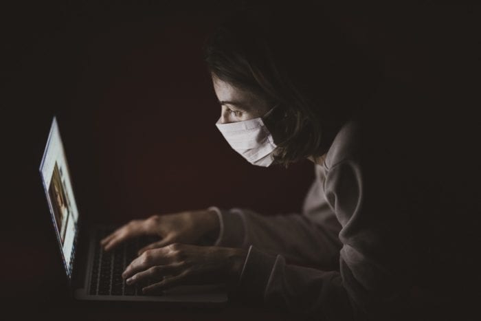 man with mask on in front of computer 