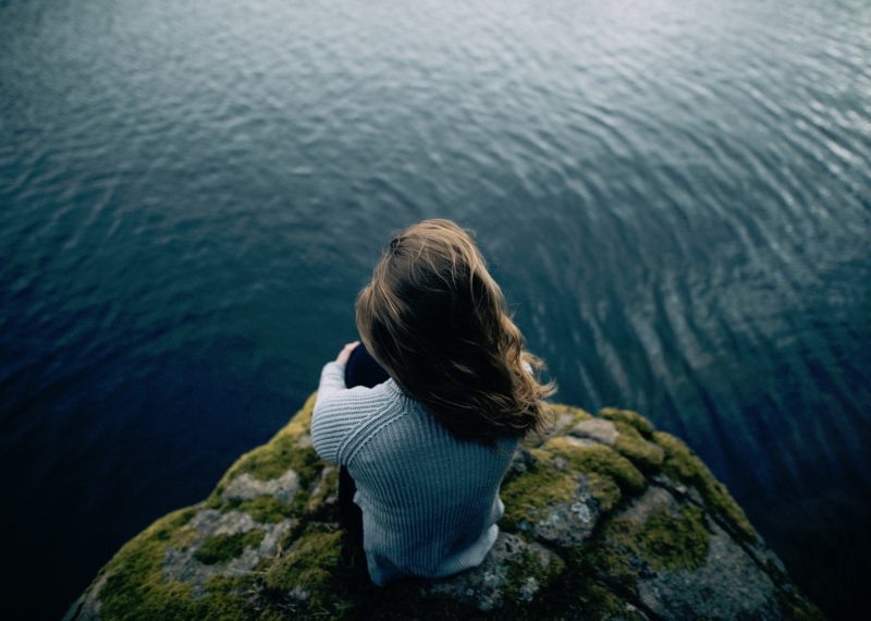 woman sitting on the edge of a cliff